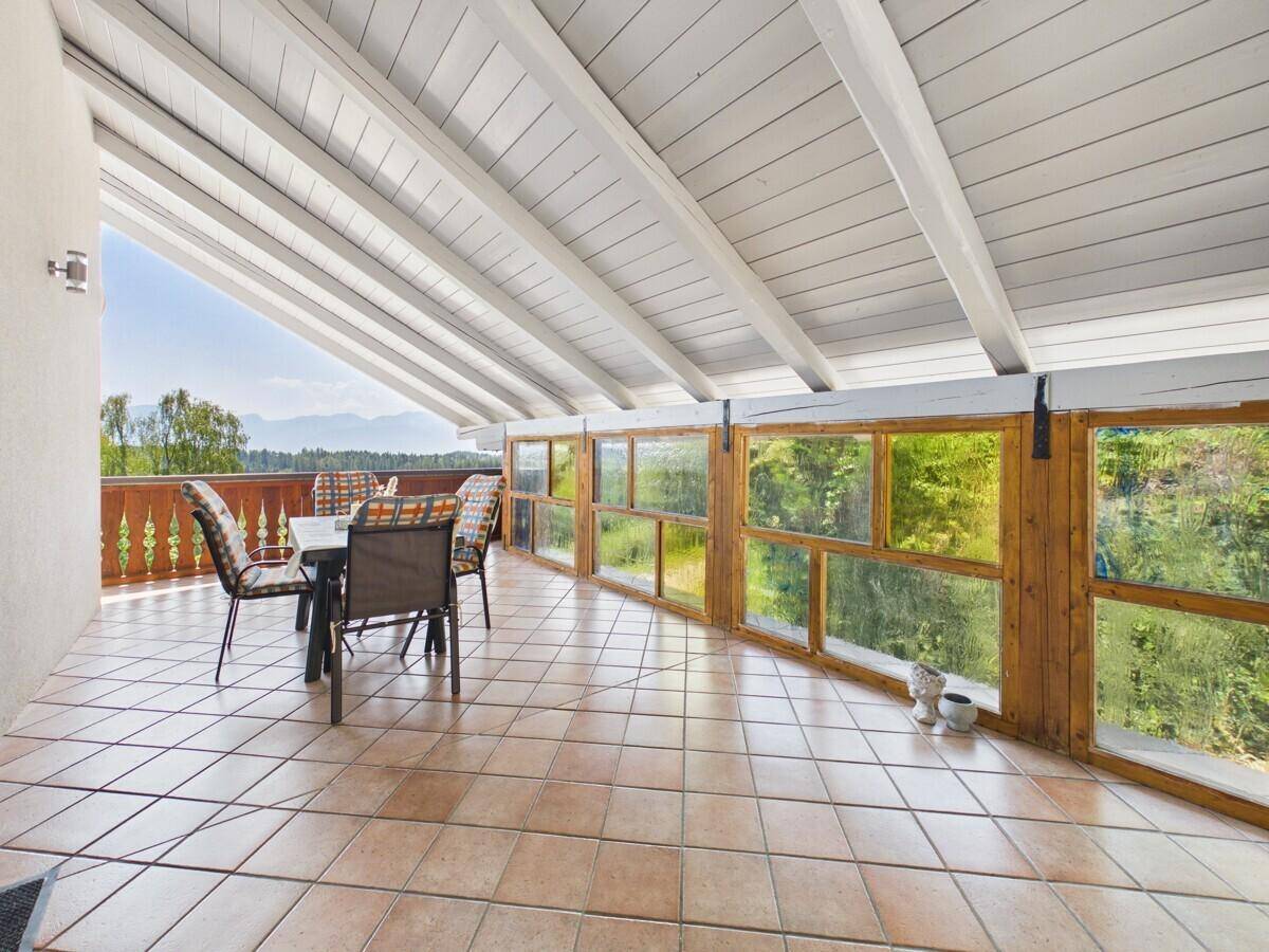 Überdachte Terrasse mit Fliesenboden und Essbereich, bietet einen weiten Blick auf die Landschaft.