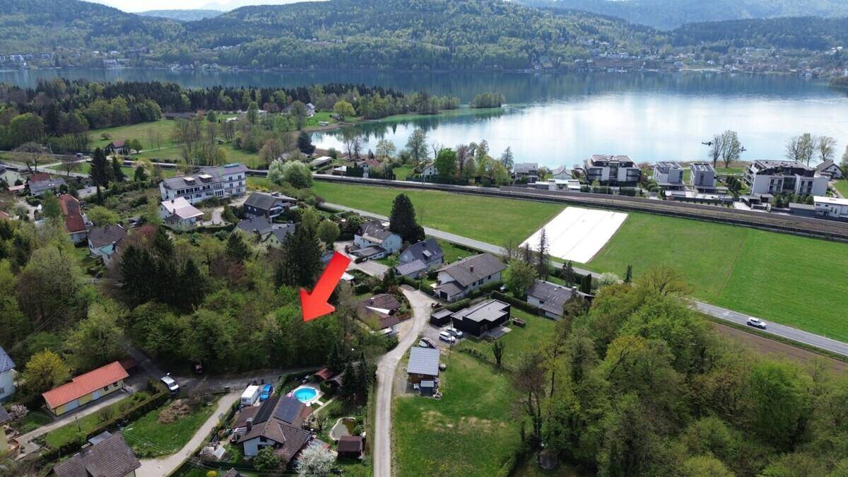 Übersichtsaufnahme aus der Luft mit rotem Pfeil, der auf das Grundstück mit Seeblick zeigt.