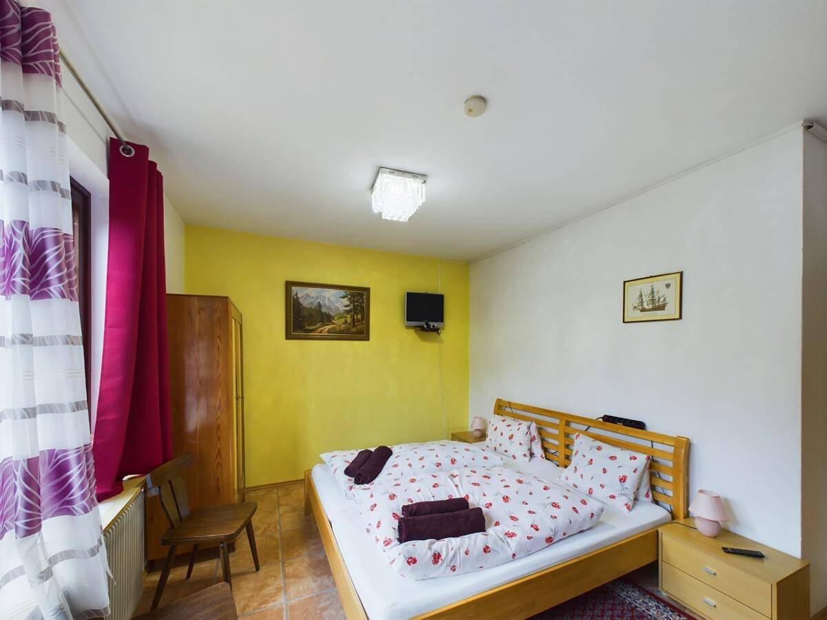 Helles Schlafzimmer mit Doppelbett, gelber Akzentwand und traditionellen Teppichen.