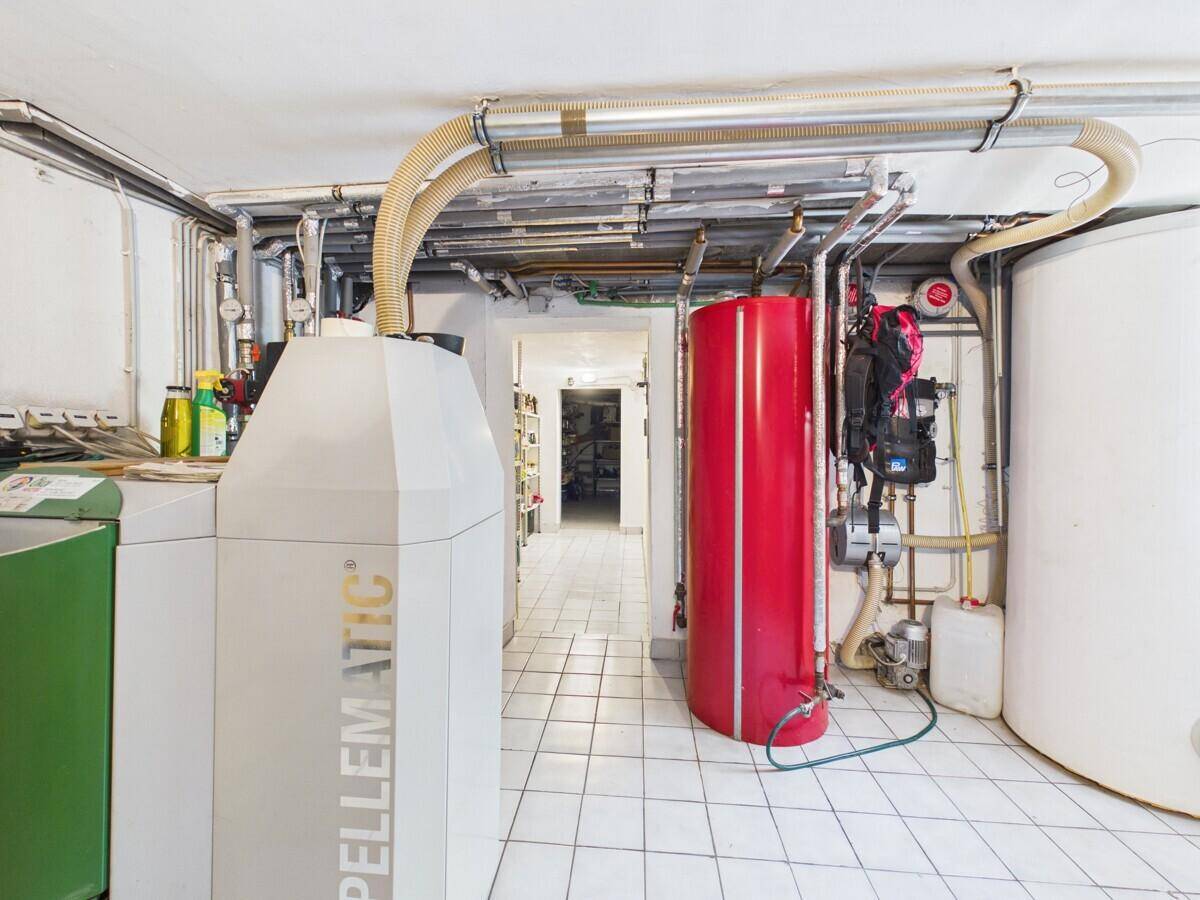 Heizungsraum im Keller mit Pelletheizung, Warmwasserspeicher und Fliesenboden.