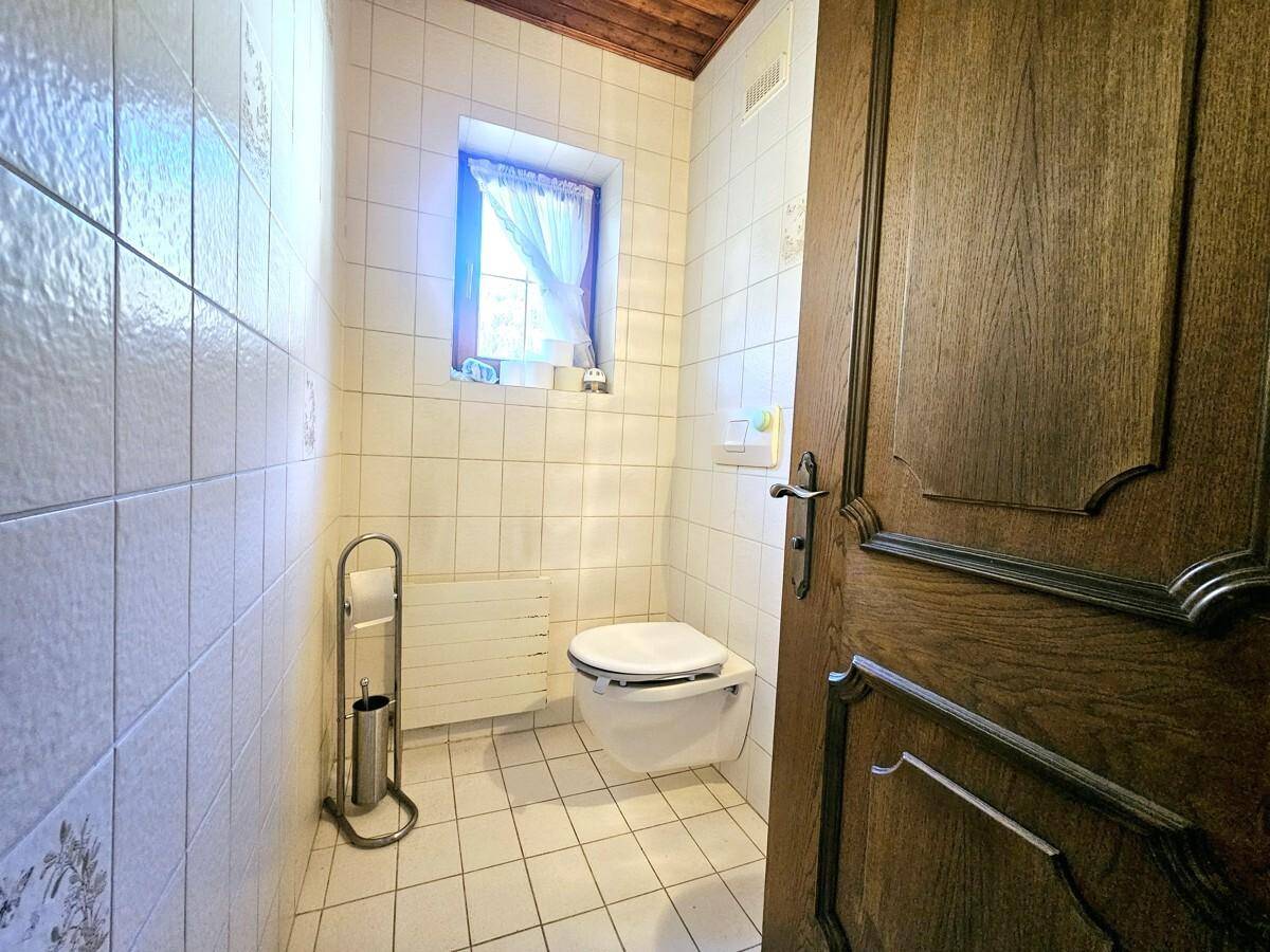 Kleines Gäste-WC mit Wand-WC, Fliesen und Fenster für Tageslicht.