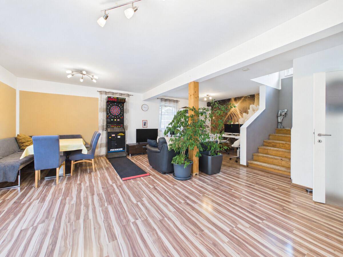 Offener Wohnbereich mit Essplatz, Sitzgelegenheiten und Treppe zum Obergeschoss.