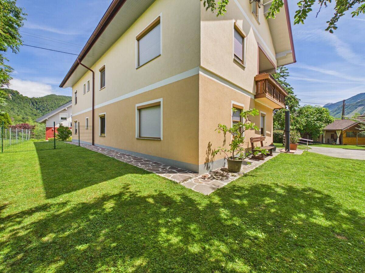 Seitenansicht des Hauses mit gepflegtem Rasen und einem kleinen Balkon im Obergeschoss.
