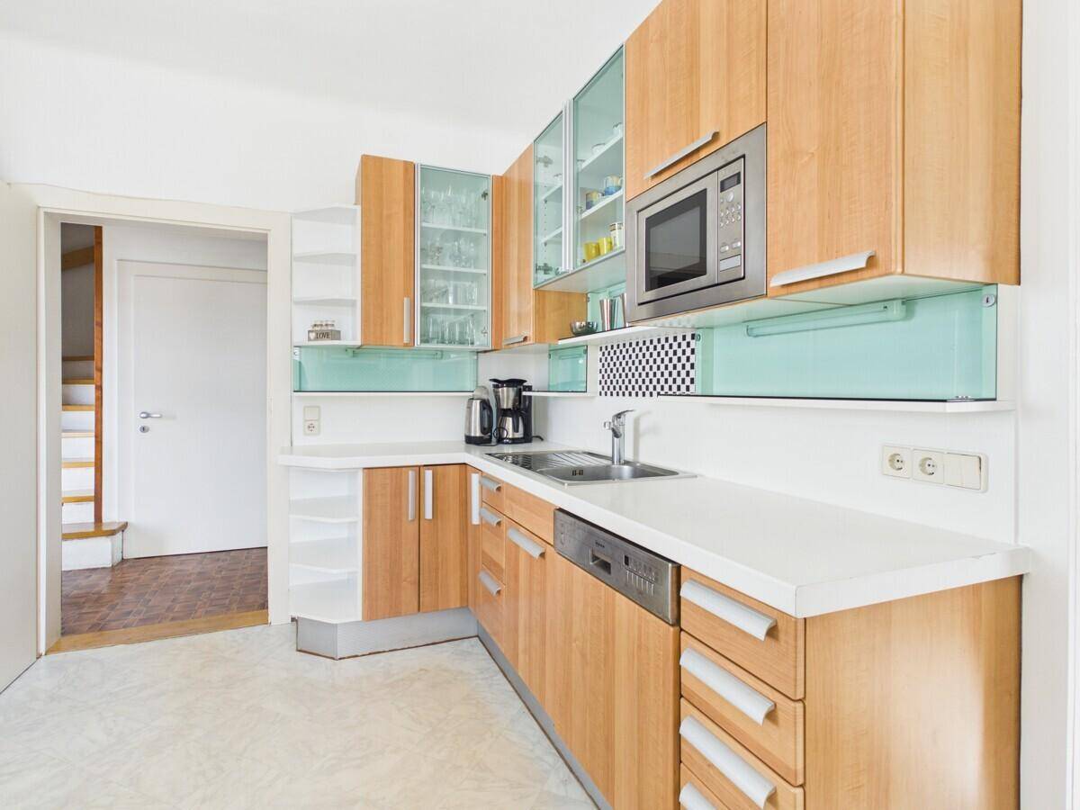 Moderne Einbauküche mit Holzfronten, Edelstahlgeräten und viel Stauraum.