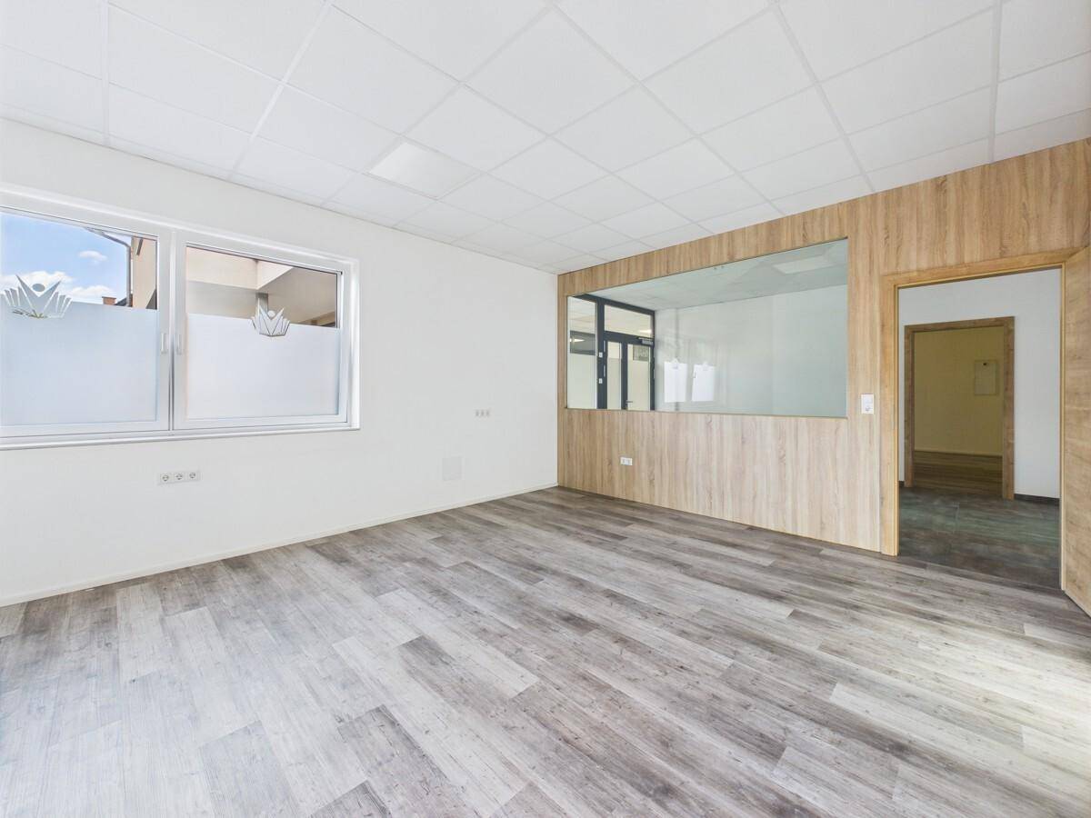 Büro mit Laminatboden, Fenster mit Sichtschutz und Blick in einen angrenzenden Raum.
