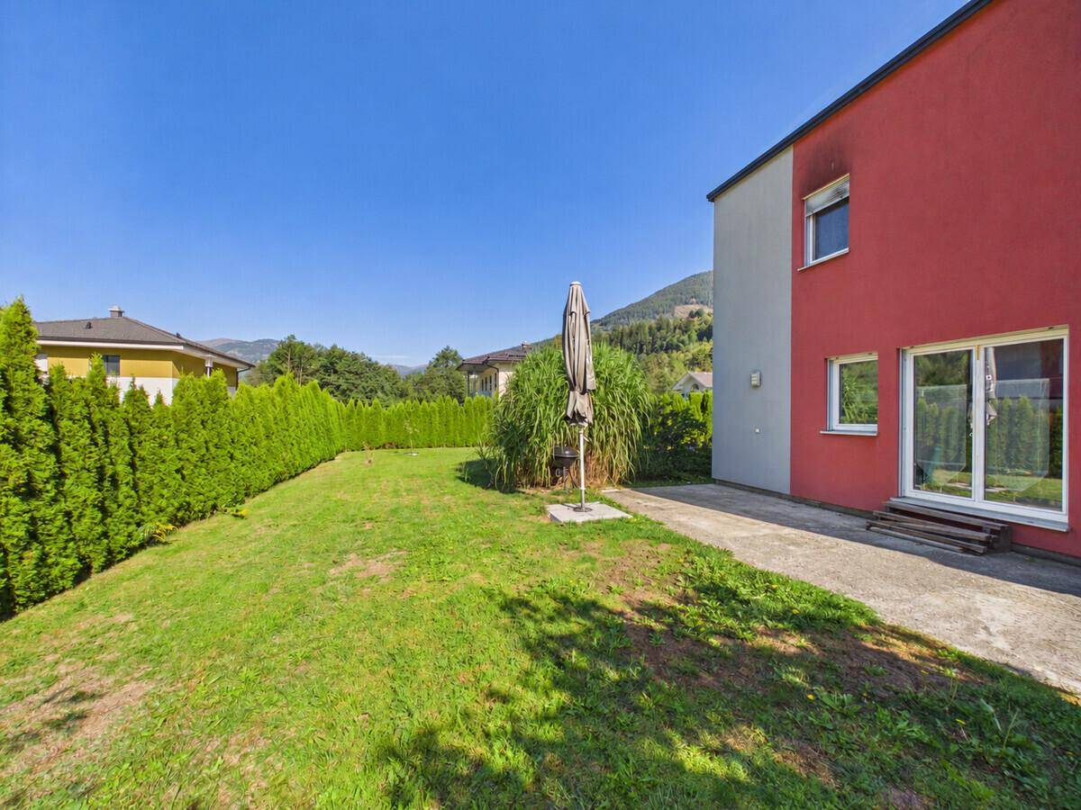 Seitliche Ansicht des Hauses mit großem Rasenbereich und einer kleinen Terrasse.