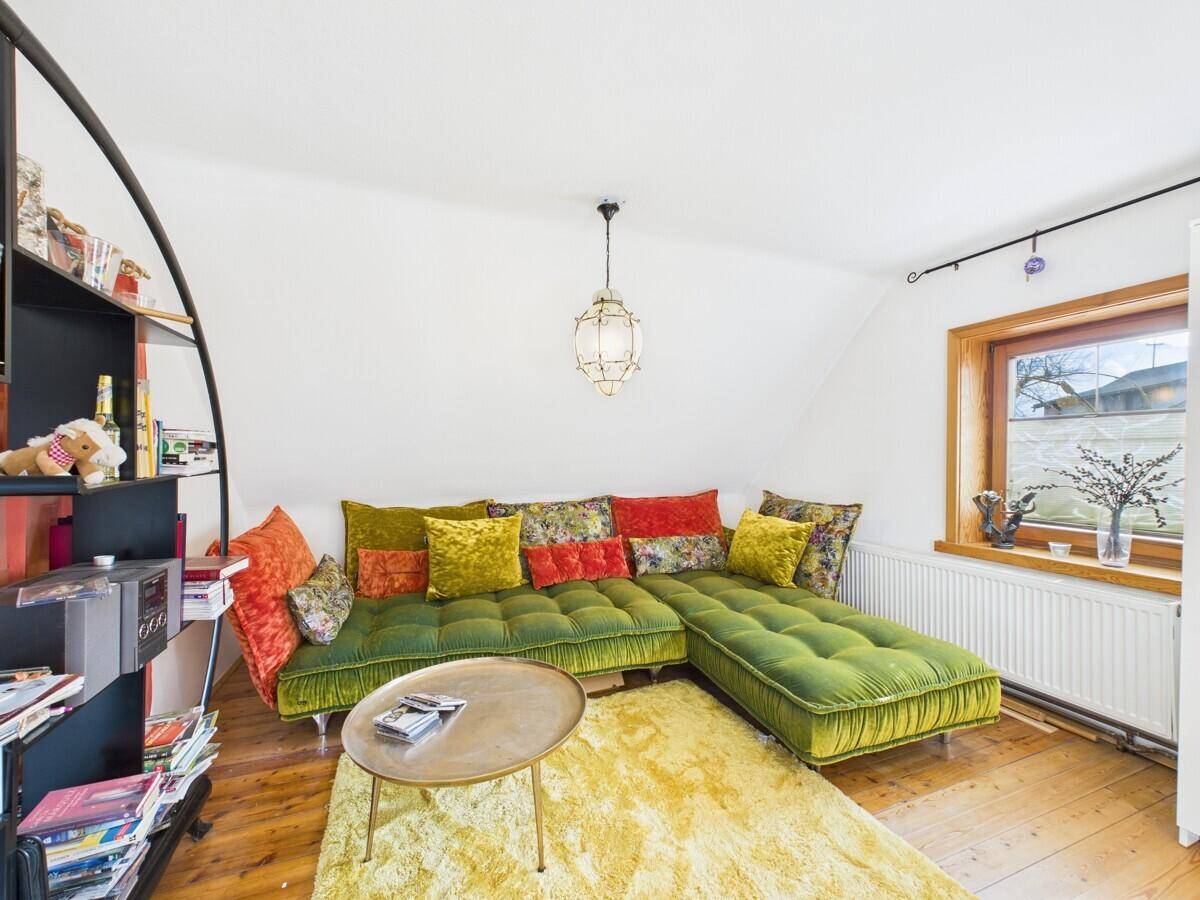 Gemütlicher Wohnbereich mit einem großen grünen Sofa, Holzboden und einem Fenster.