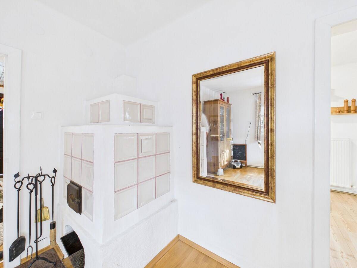 Eingangsbereich mit einem traditionellen Kachelofen und einem großen Wandspiegel.