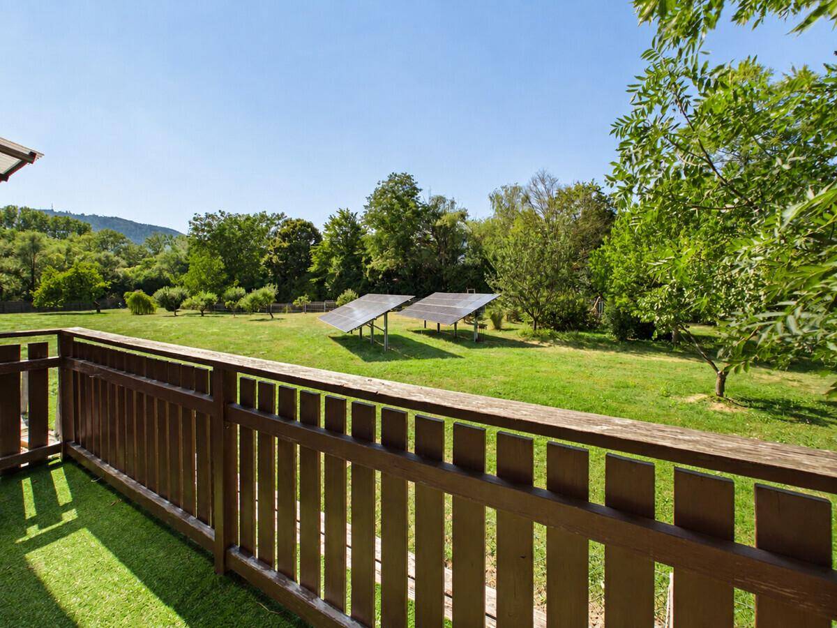 Balkon mit Holzbalkon und Blick auf eine weite Grünfläche mit Solaranlagen.