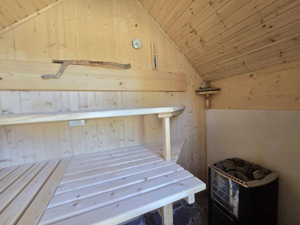 Helle Holzsauna mit Bänken und Saunaofen, bereit für entspannende Momente.