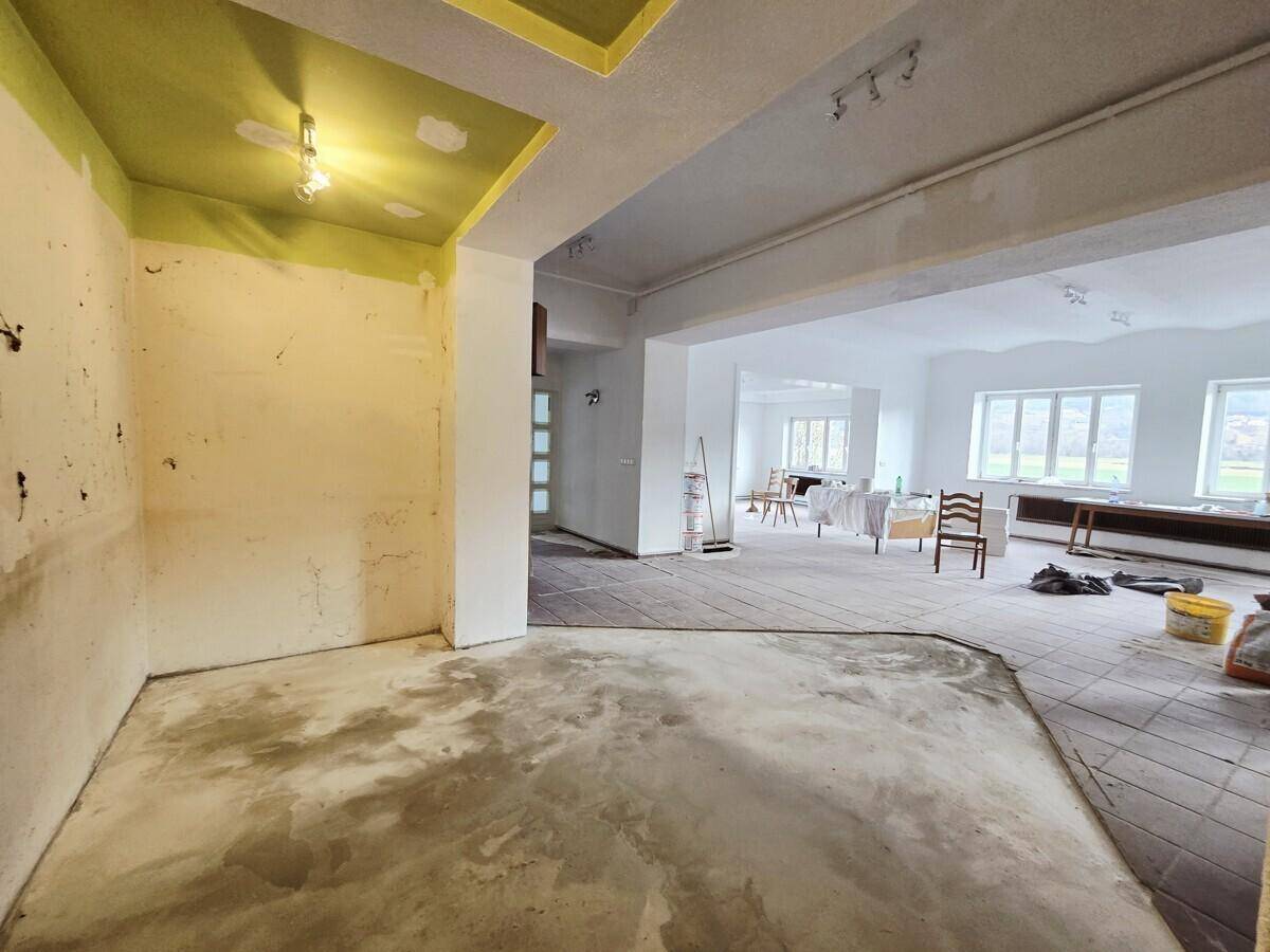 Renovierungsbedürftiger Raum mit Betonboden und teilweise gestrichenen Wänden, der auf eine Modernisierung wartet.