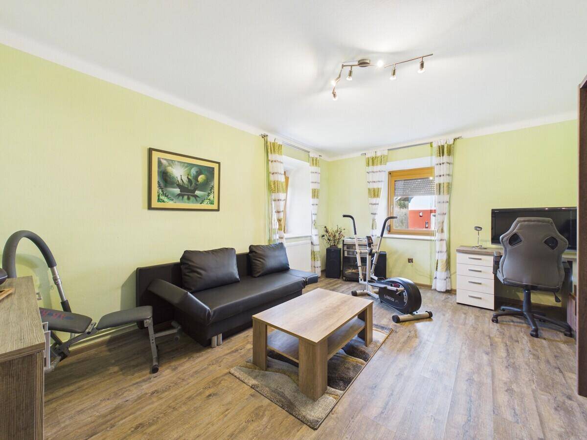Vielseitiger Raum als Büro und Fitnessbereich mit Sofa und Laminatboden genutzt.