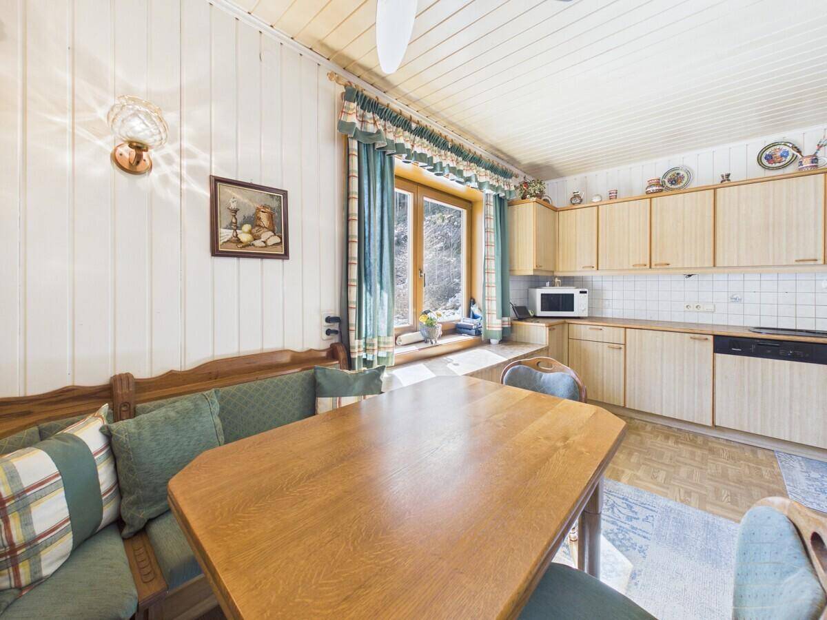 Gemütlicher Essbereich in der Küche mit Holztisch, Eckbank und Blick ins Grüne.