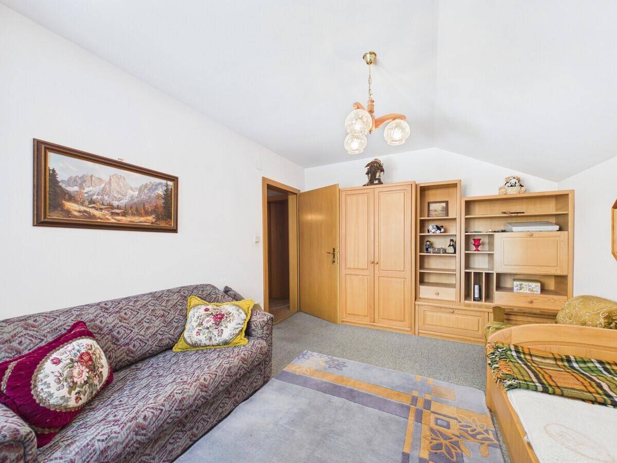 Schlafzimmer im Dachgeschoss mit Sofa, Bett und Holzmöbeln, bietet eine wohnliche Atmosphäre.