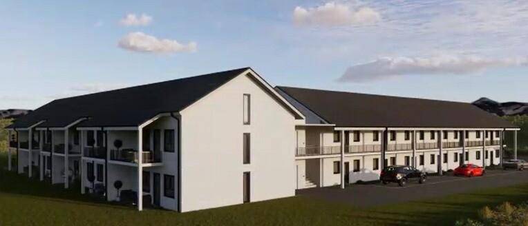 Lange Gebäudefassade der modernen Wohnanlage mit Balkonen und gepflegter Grünfläche.