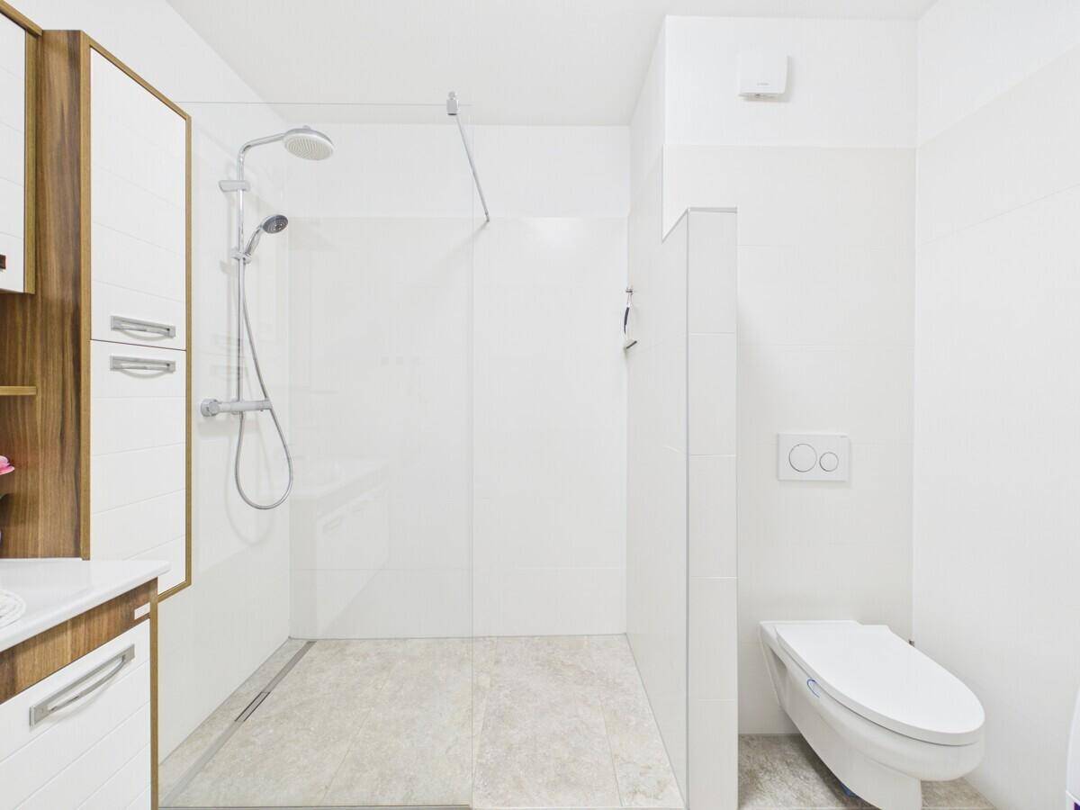 Helles Badezimmer mit begehbarer Dusche und wandhängendem WC.