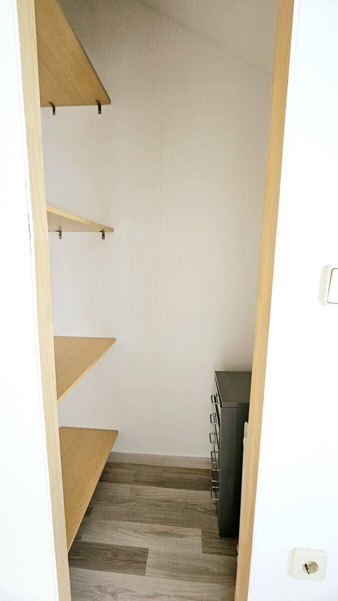 Kleiner Abstellraum mit Holzregalen und Laminatboden, ideal für zusätzlichen Stauraum.
