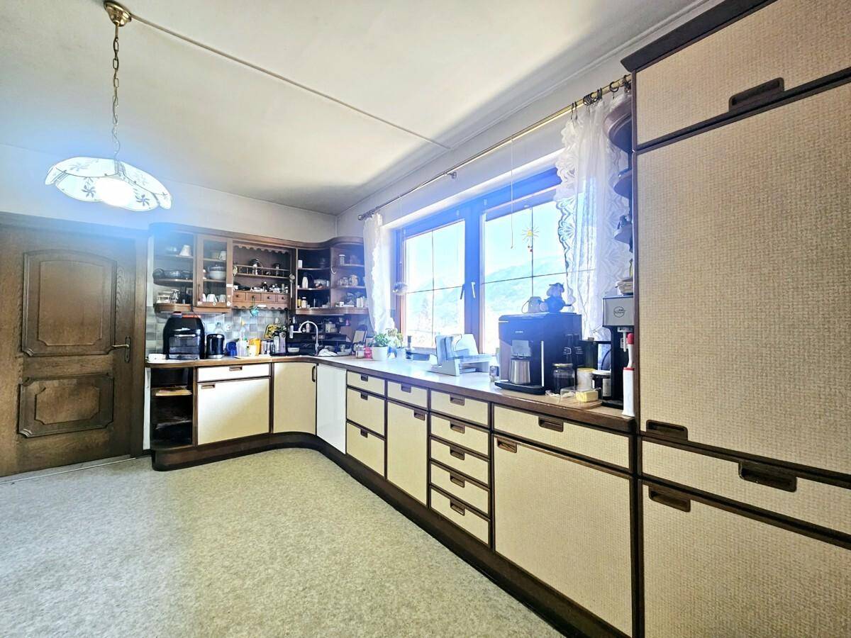 Geräumige Küche mit vielen Schränken, Arbeitsflächen und großem Fenster.