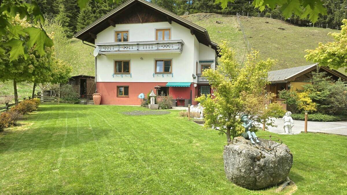 Traditionelles Haus mit großem grünen Garten und Bergblick in ländlicher Umgebung.