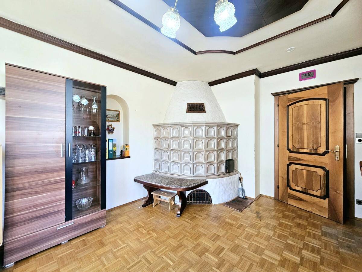 Gemütliches Wohnzimmer mit traditionellem Kachelofen, Parkettboden und Holztüren.