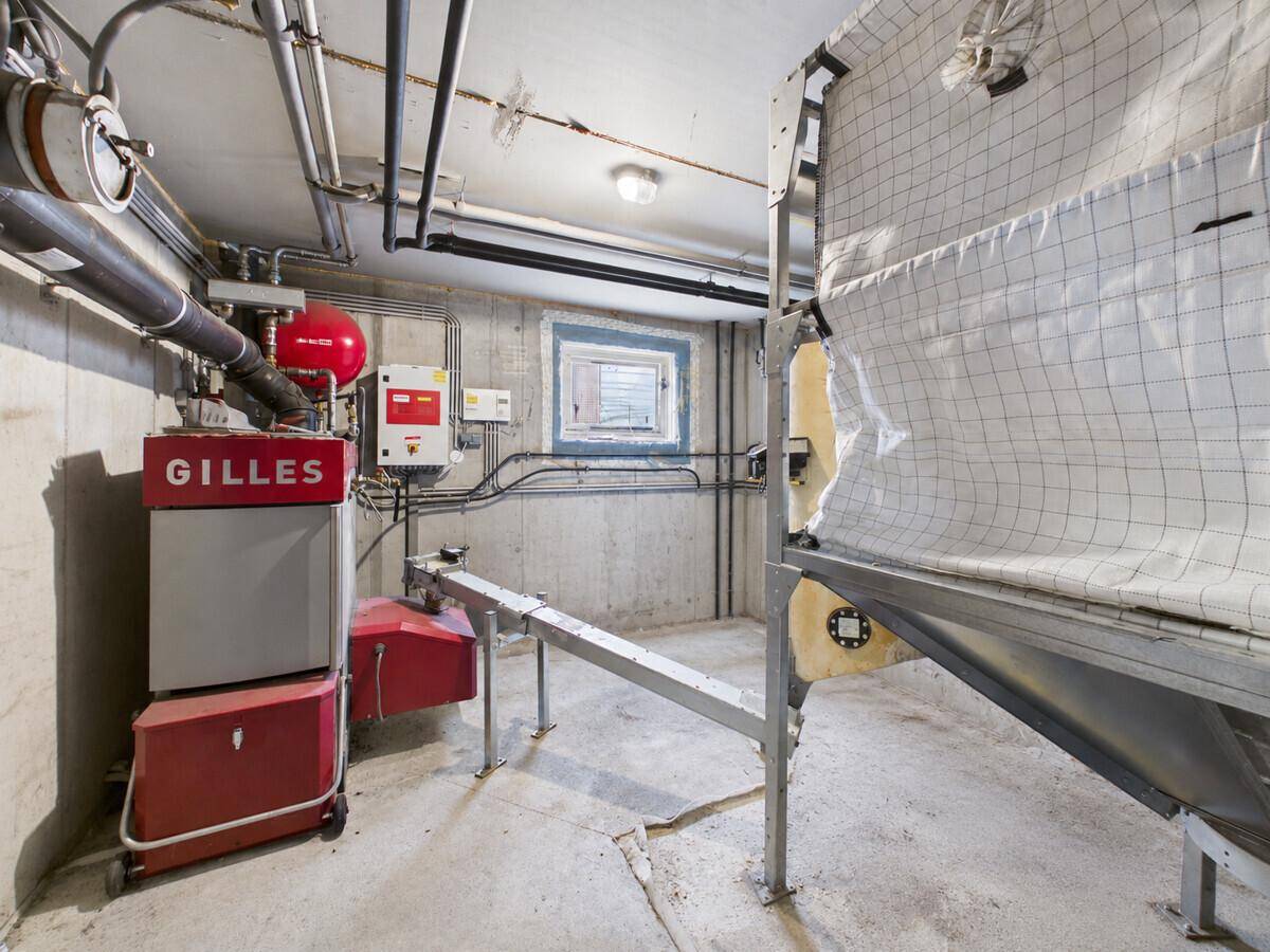 Funktionaler Heizraum im Keller mit Pelletheizung, Lagersilo und sichtbaren Installationen.