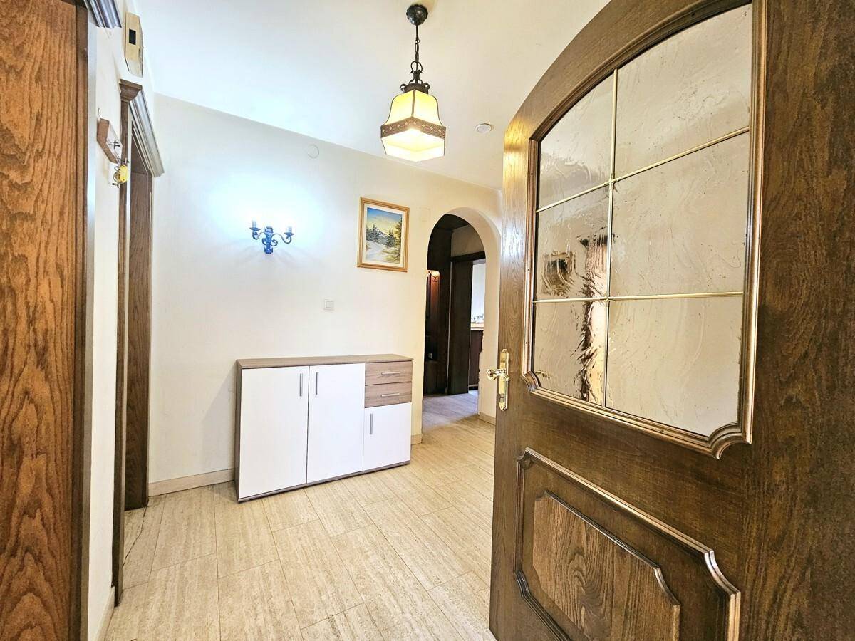 Heller Eingangsbereich mit Fliesenboden, Garderobe und Holztüren.
