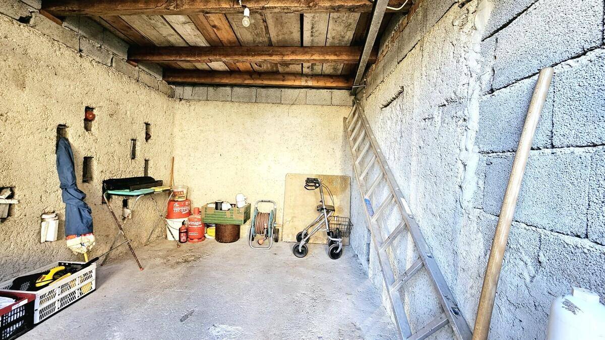 Rustikaler Abstellraum im Keller mit Holzbalken und Steinwänden.