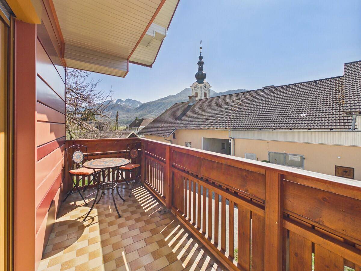 Kleiner Balkon mit gemütlicher Sitzecke und Blick auf die Kirche sowie die Berge.