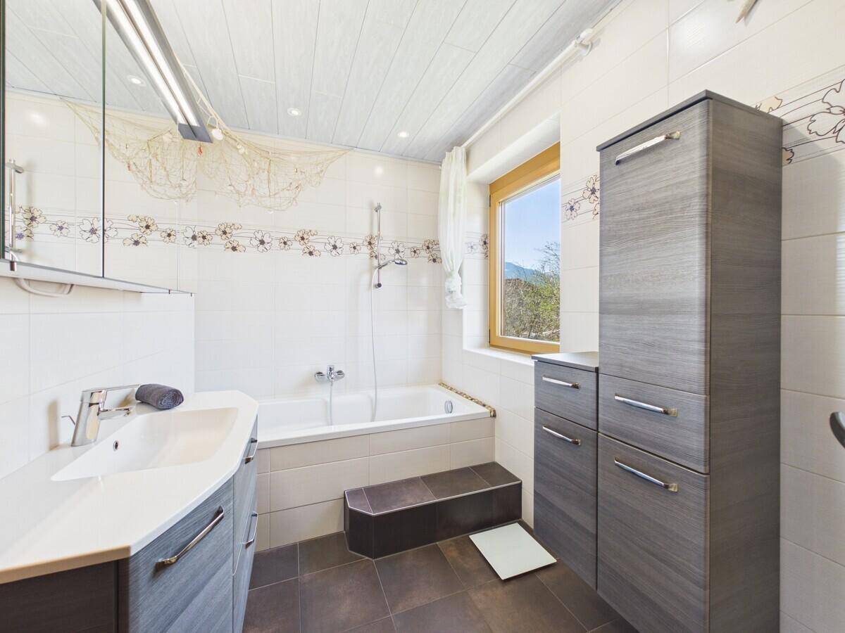 Badezimmer mit Badewanne, modernem Waschtisch und Fenster mit Bergblick.
