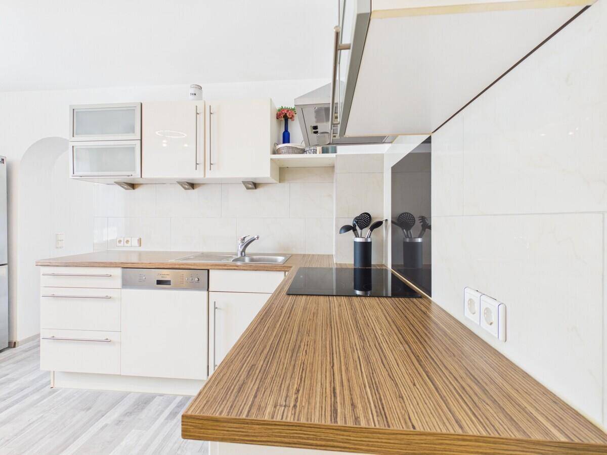 Funktionale Küche mit hellen Holz-Arbeitsplatten, weißen Schränken und modernen Geräten.