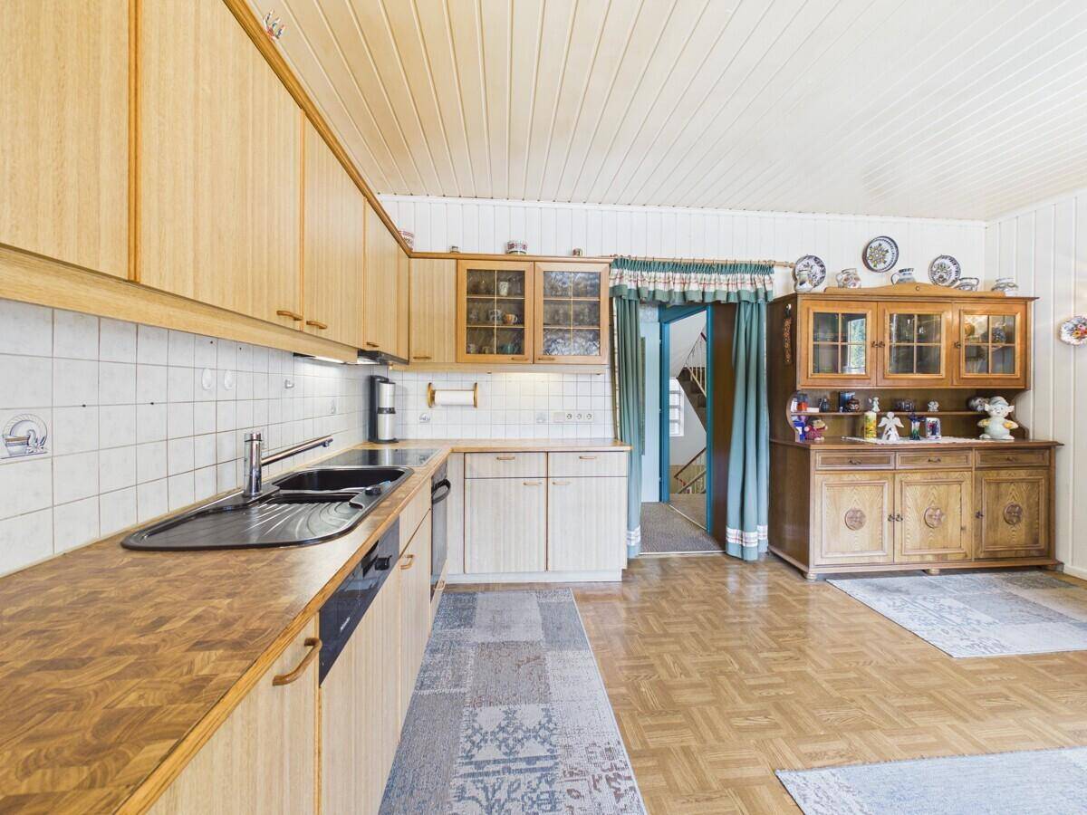 Funktionale Küche mit Holztheke, weißen Fliesen und traditionellem Geschirrschrank.