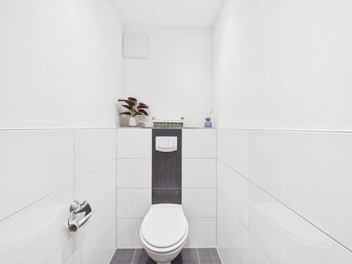 Schlichtes Gäste-WC mit wandhängender Toilette und minimalistischem Design.