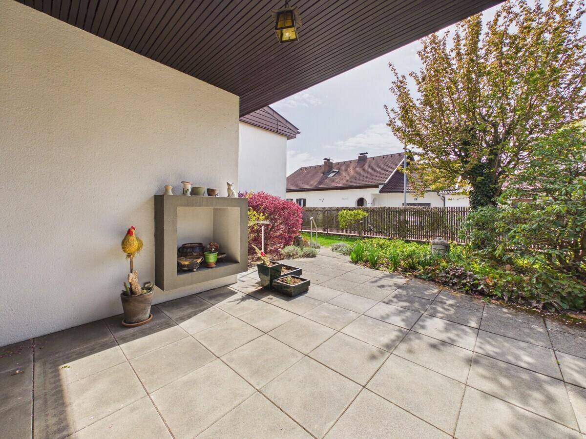 Überdachte Terrasse mit Fliesenboden und integriertem Außenkamin.