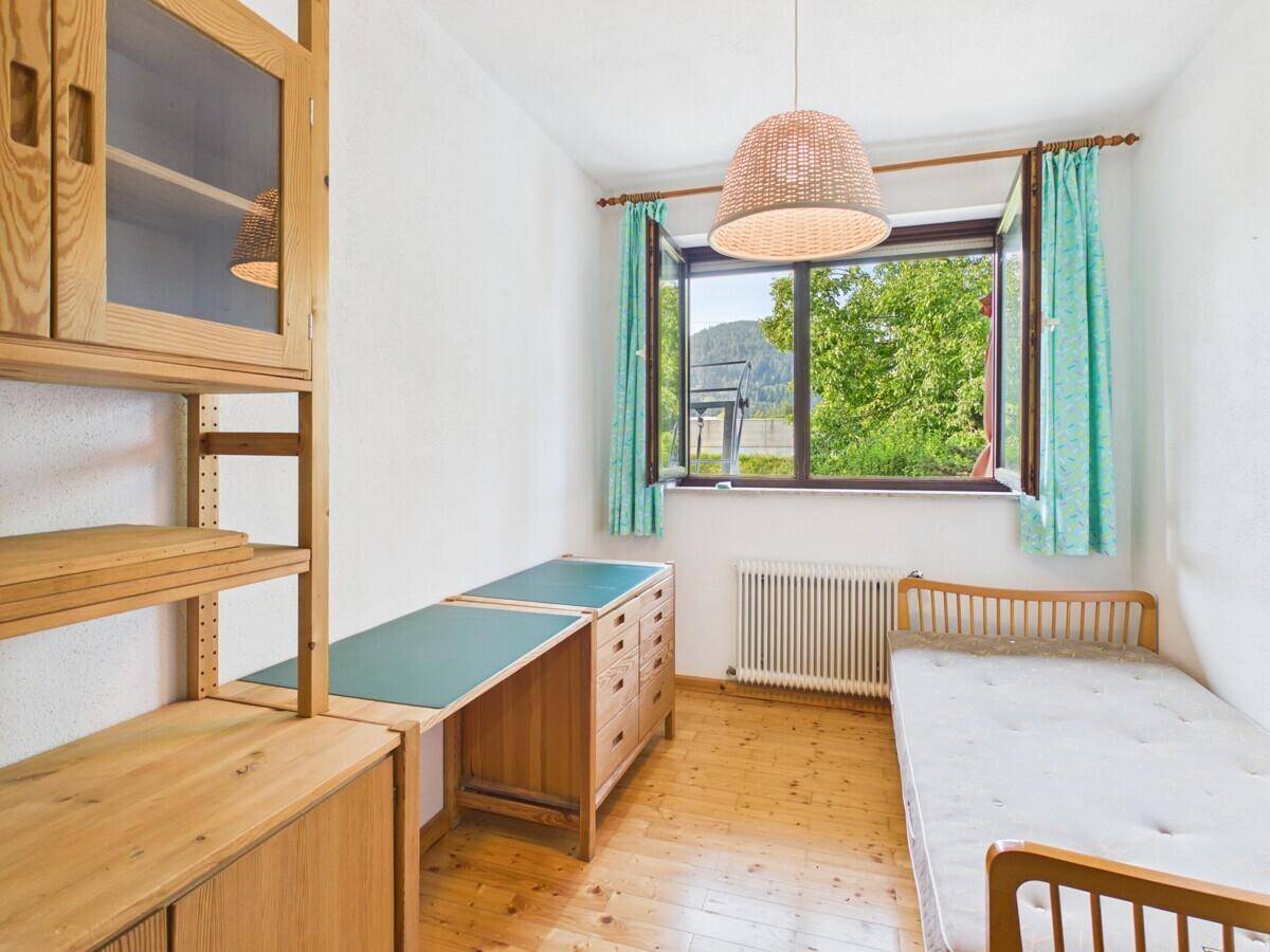 Gemütliches Schlafzimmer mit Holzboden, Schreibtisch und Fenster mit Blick auf die Landschaft.