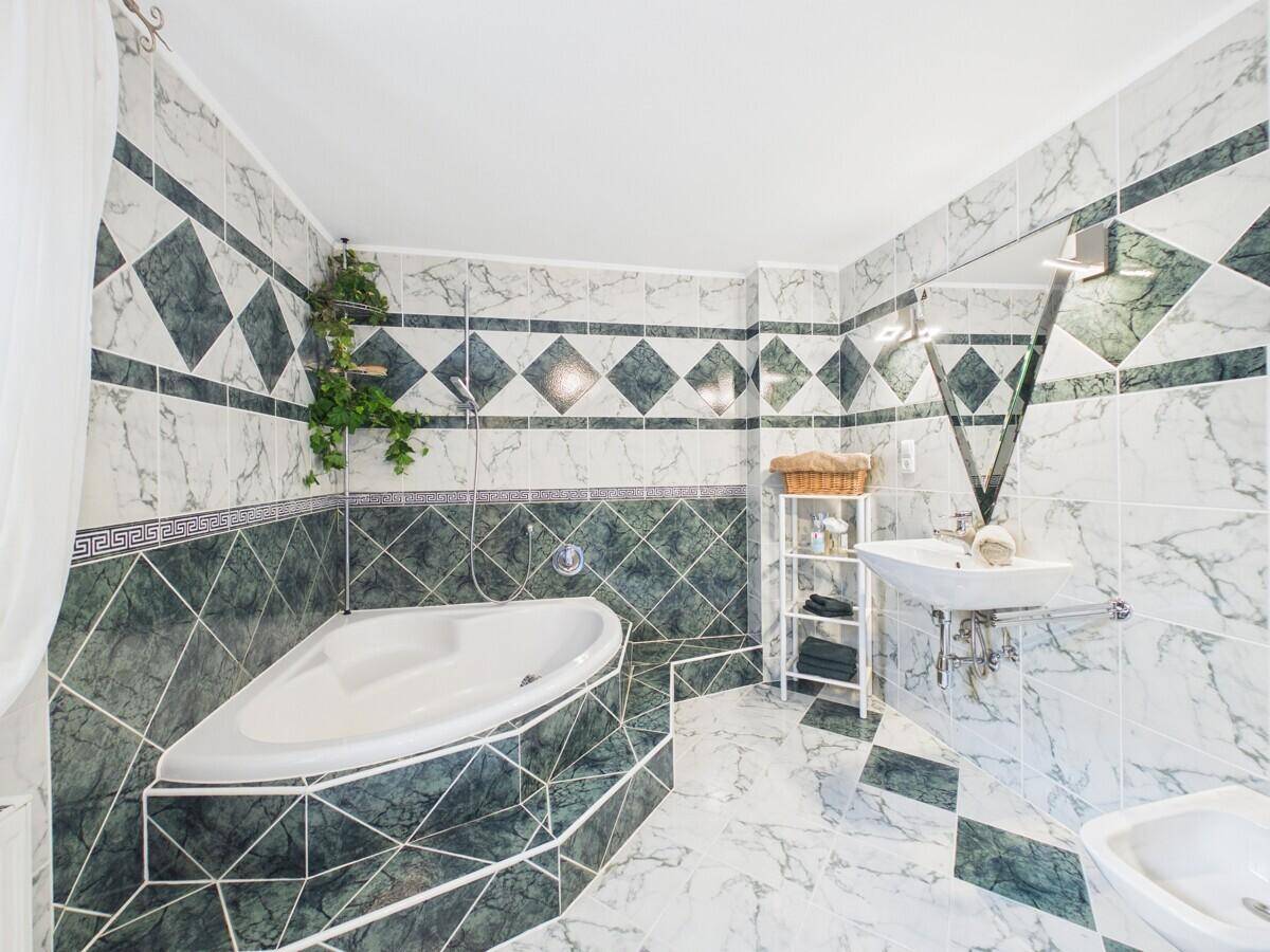 Großes Badezimmer mit Eckbadewanne, Bidet und markanten grün-weißen Marmorfliesen.