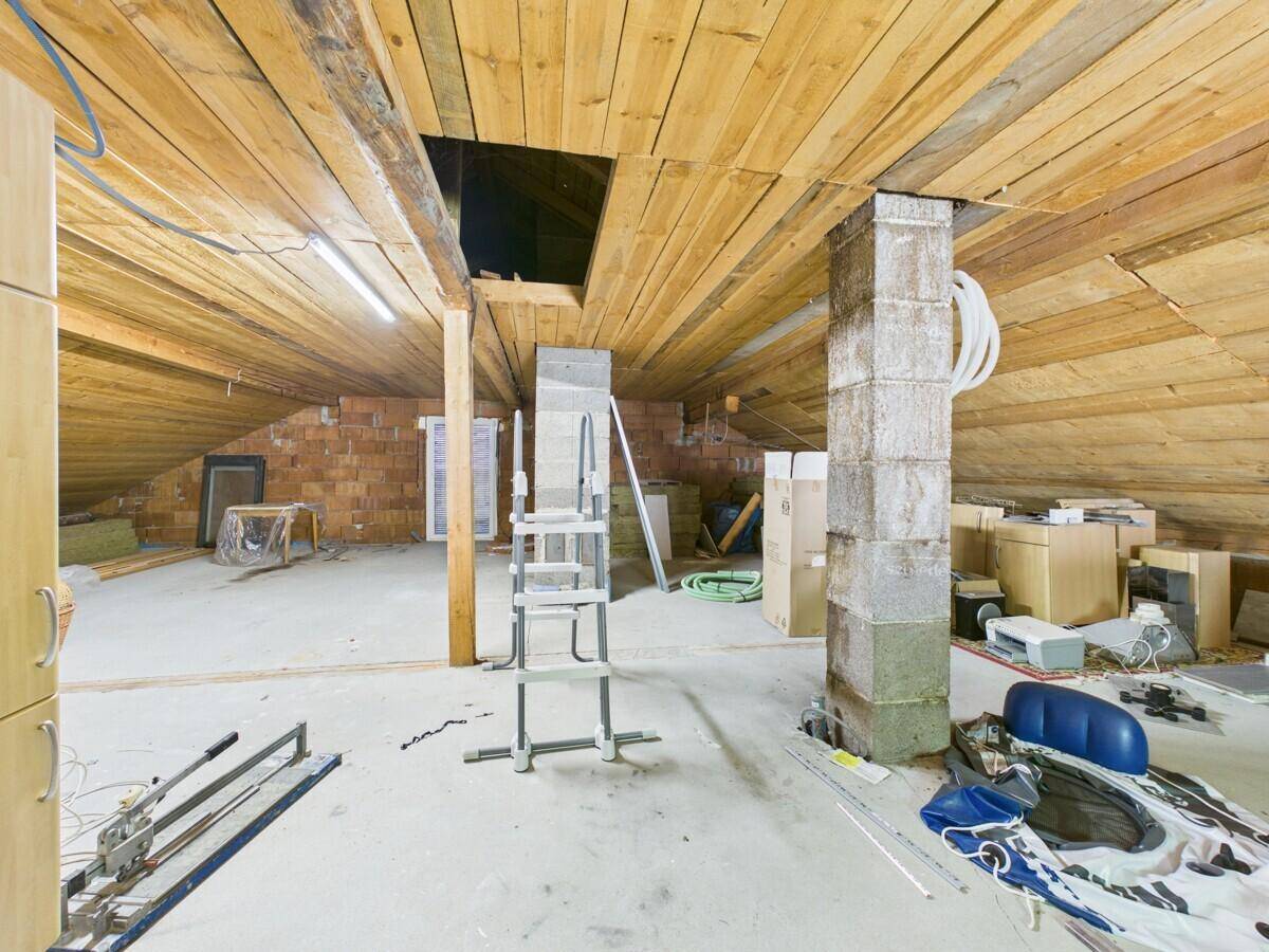 Geräumiger Dachboden mit sichtbaren Holzbalken und Baumaterialien, bereit für den Ausbau.