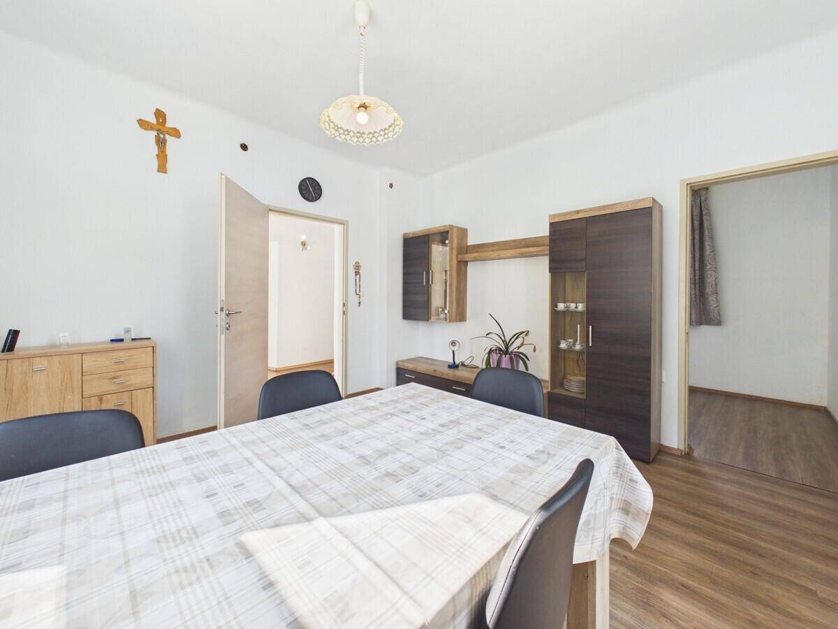 Essbereich mit Esstisch und Schrankwand, dekoriert mit einem Kruzifix an der Wand.