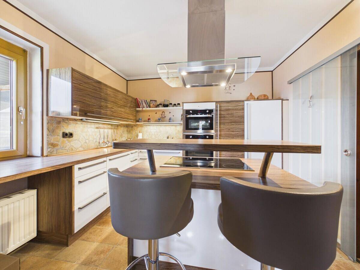 Moderne Küche mit Holz- und weißen Fronten, Kochinsel und Barhockern.
