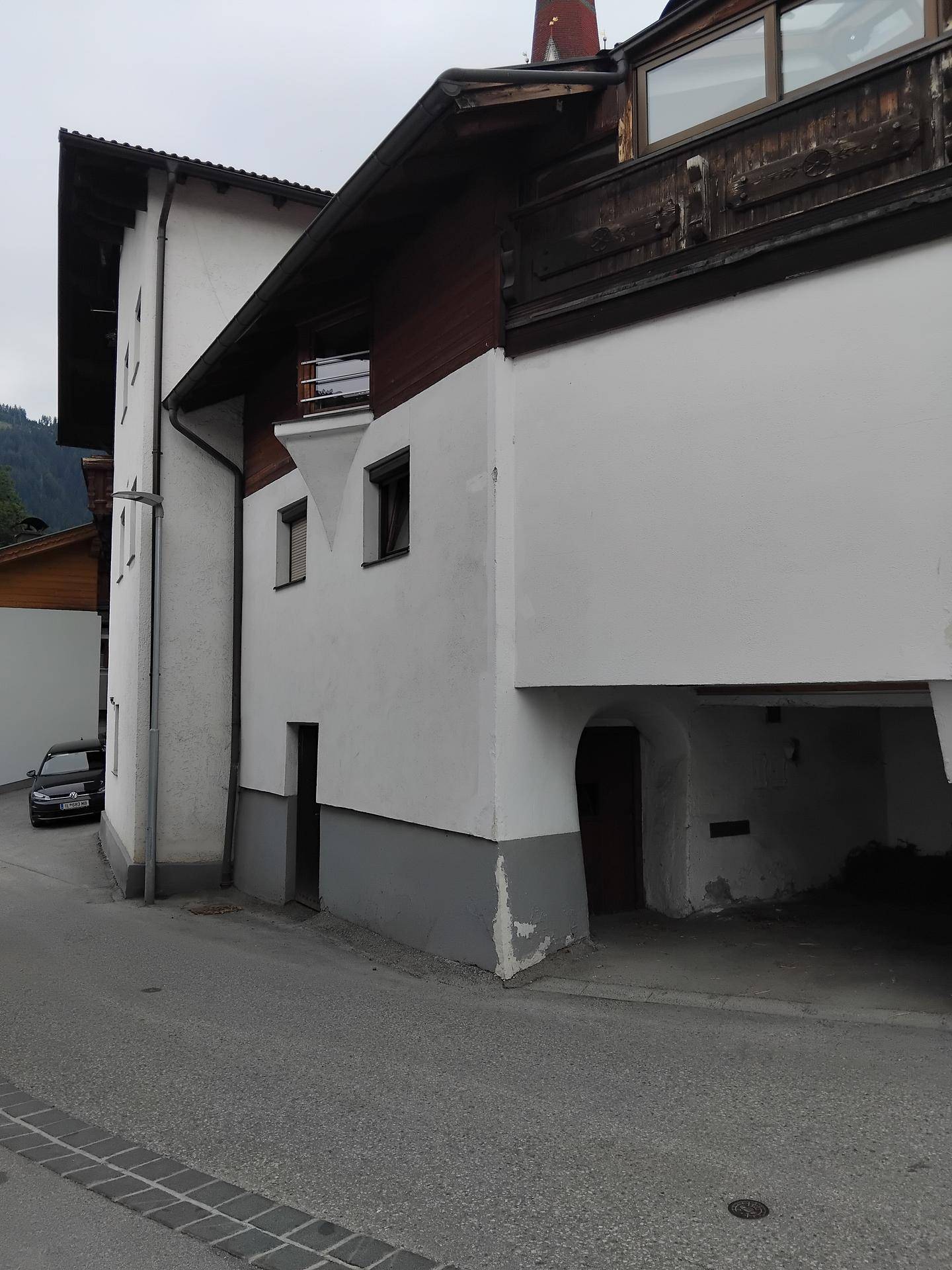 Seitenansicht des traditionellen Gebäudes mit überdachter Durchfahrt und Holzelementen.