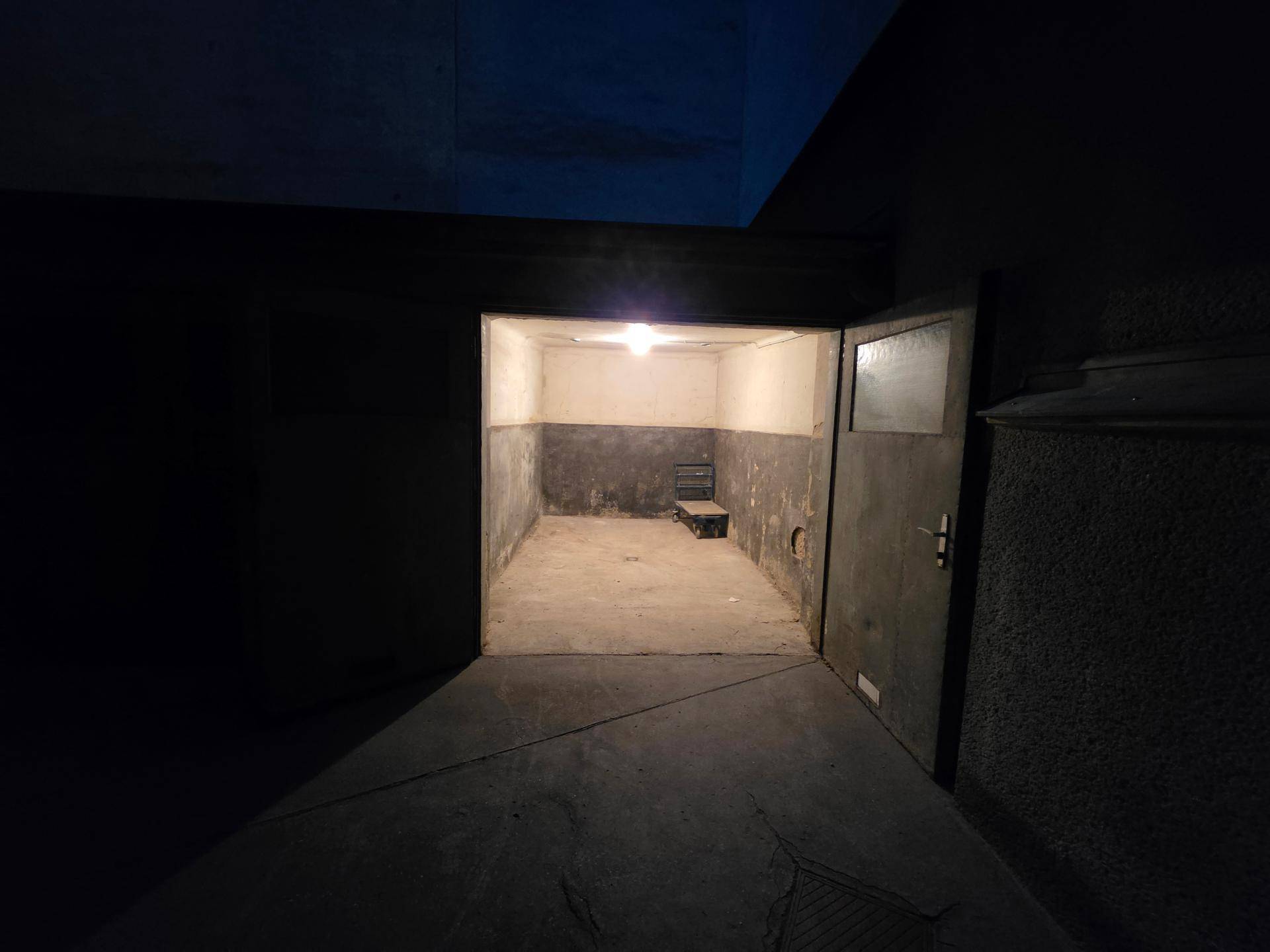 Innenansicht einer leeren, schwach beleuchteten Garage oder eines Lagerraums mit einer Bank.