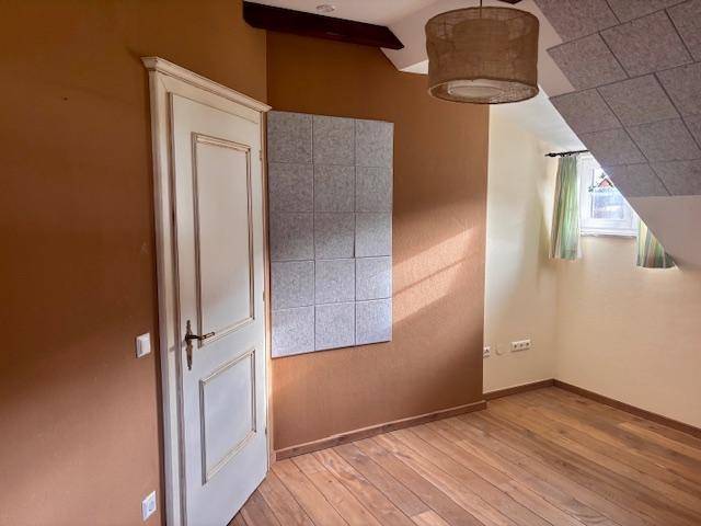Schlafzimmer mit Holzboden, brauner Wand und schrägen Decken, mit Fenster.