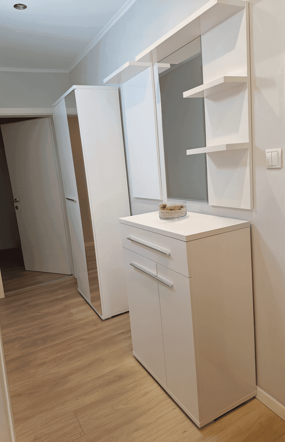 Heller Flur mit modernem Schuhschrank, großem Spiegel und weißem Kleiderschrank.