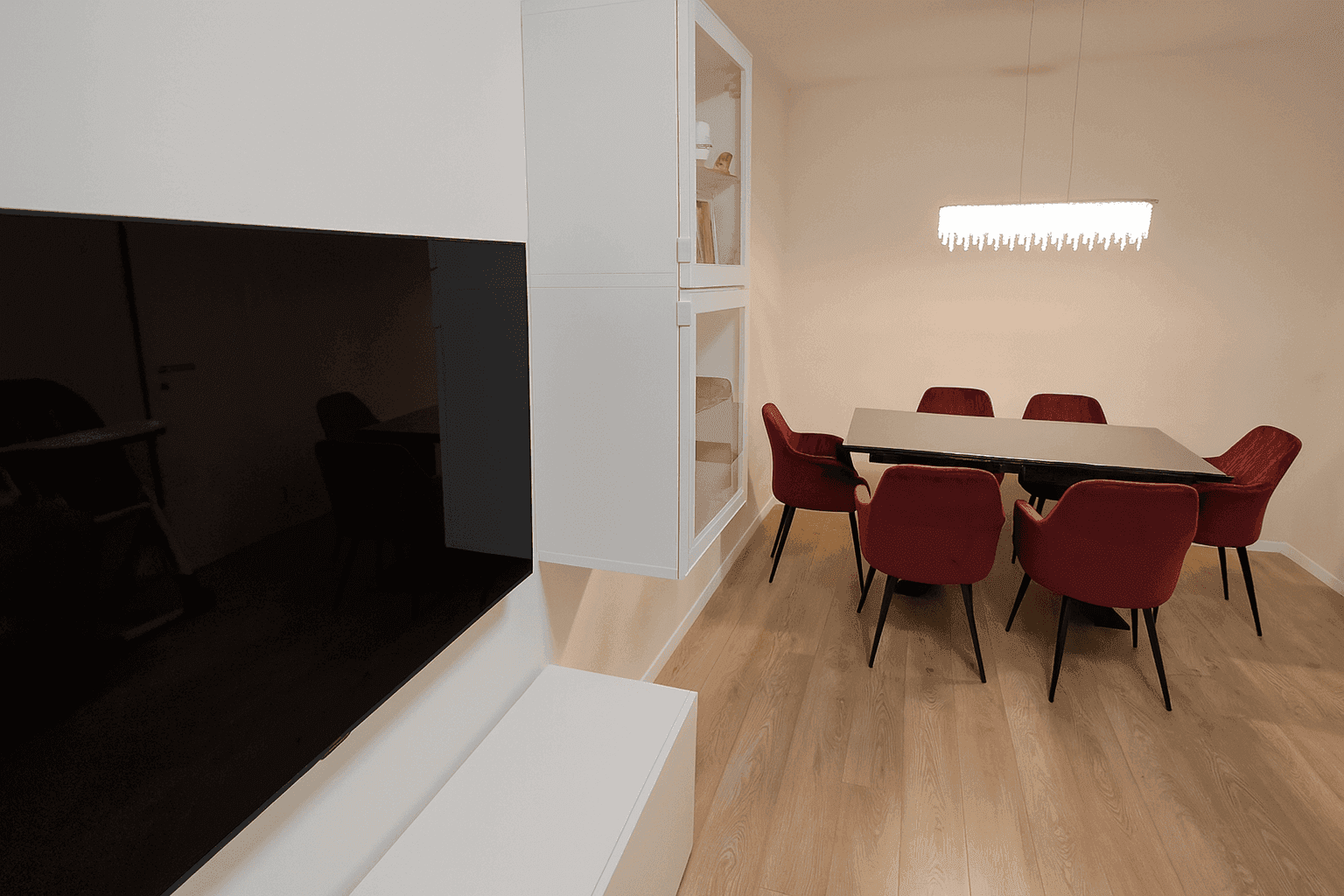 Eleganter Essbereich mit großem Tisch, roten Stühlen und moderner Deckenleuchte.