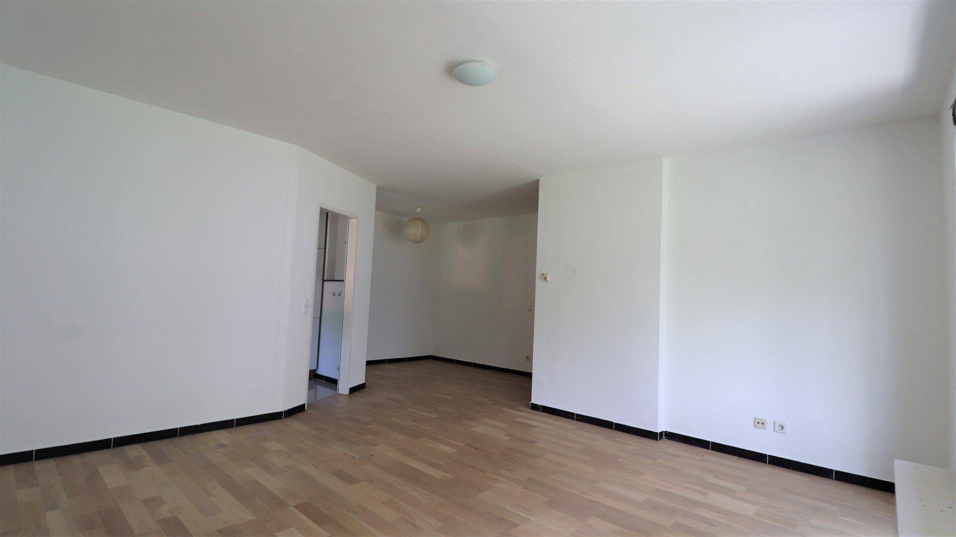 Leerer Wohnraum mit hellem Parkettboden und weißen Wänden, bereit zur individuellen Gestaltung.