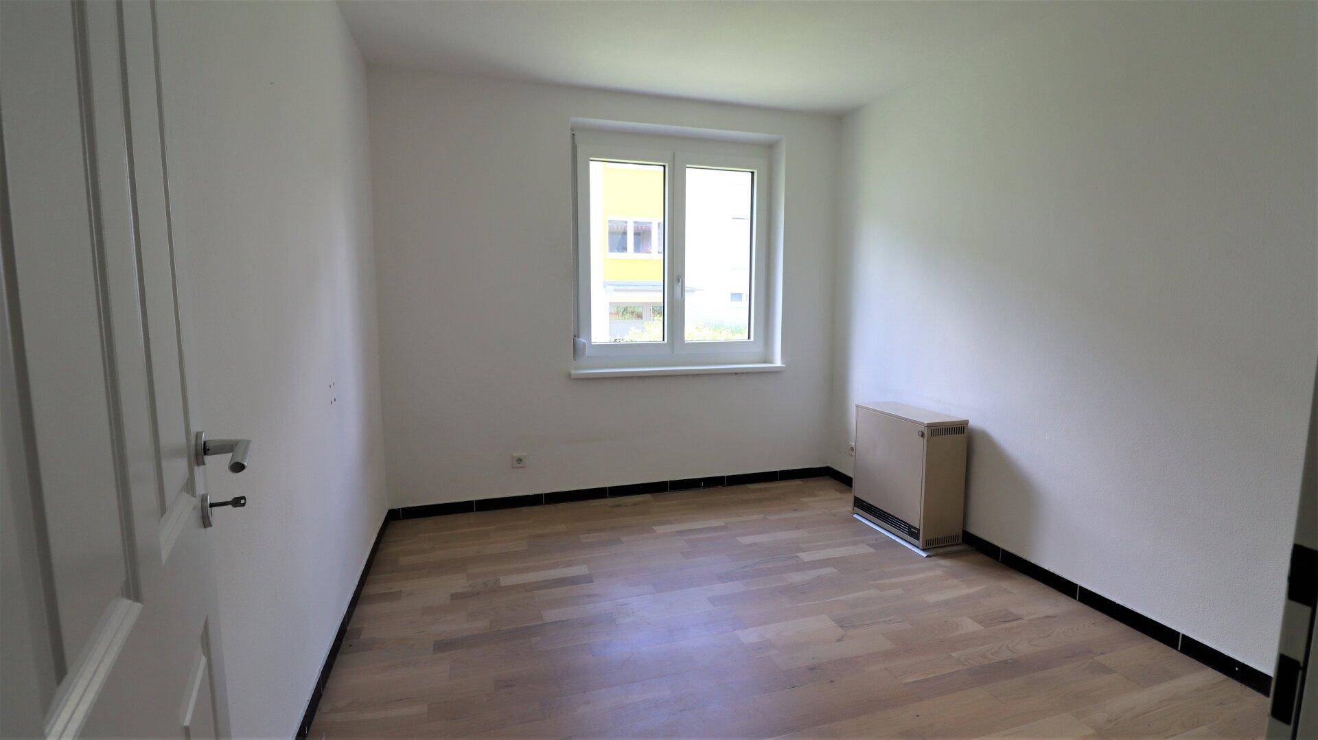 Leeres Schlafzimmer mit hellem Parkettboden und weiß gestrichenen Wänden, bereit zur Einrichtung.