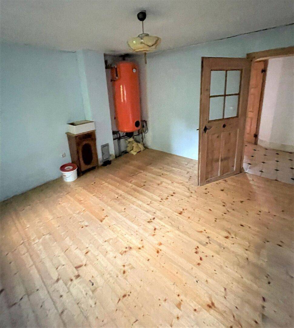 Raum mit Holzboden, Warmwasserboiler und Zugang zu weiteren Bereichen.