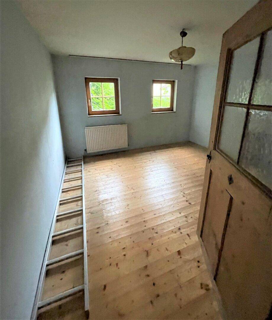 Schlafzimmer mit Holzboden, hellblauen Wänden und zwei Fenstern für natürliches Licht.