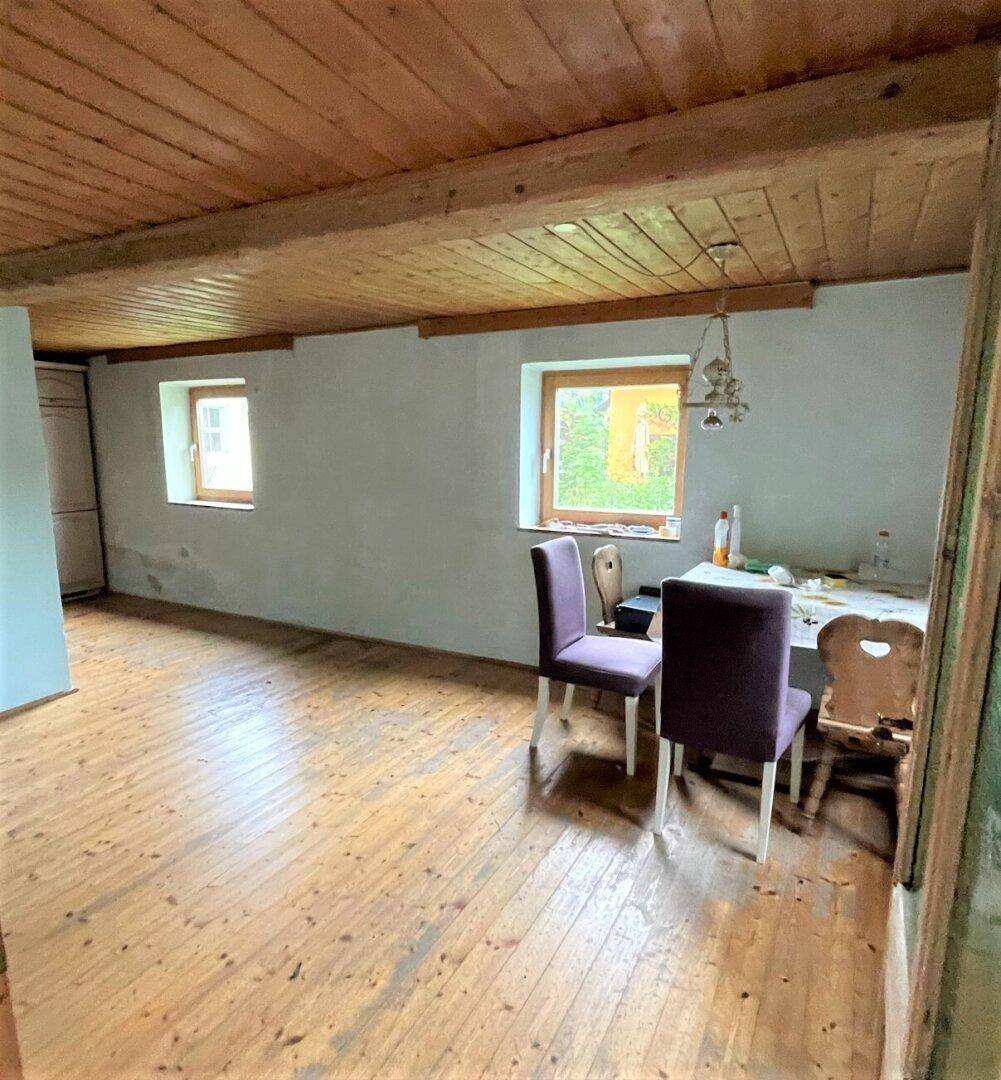 Essbereich mit Holzboden, Holzdecke und Blick ins Grüne durch die Fenster.