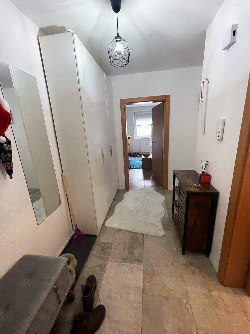 Heller Flur mit Fliesenboden, großem weißen Kleiderschrank und einem kleinen Konsolentisch.