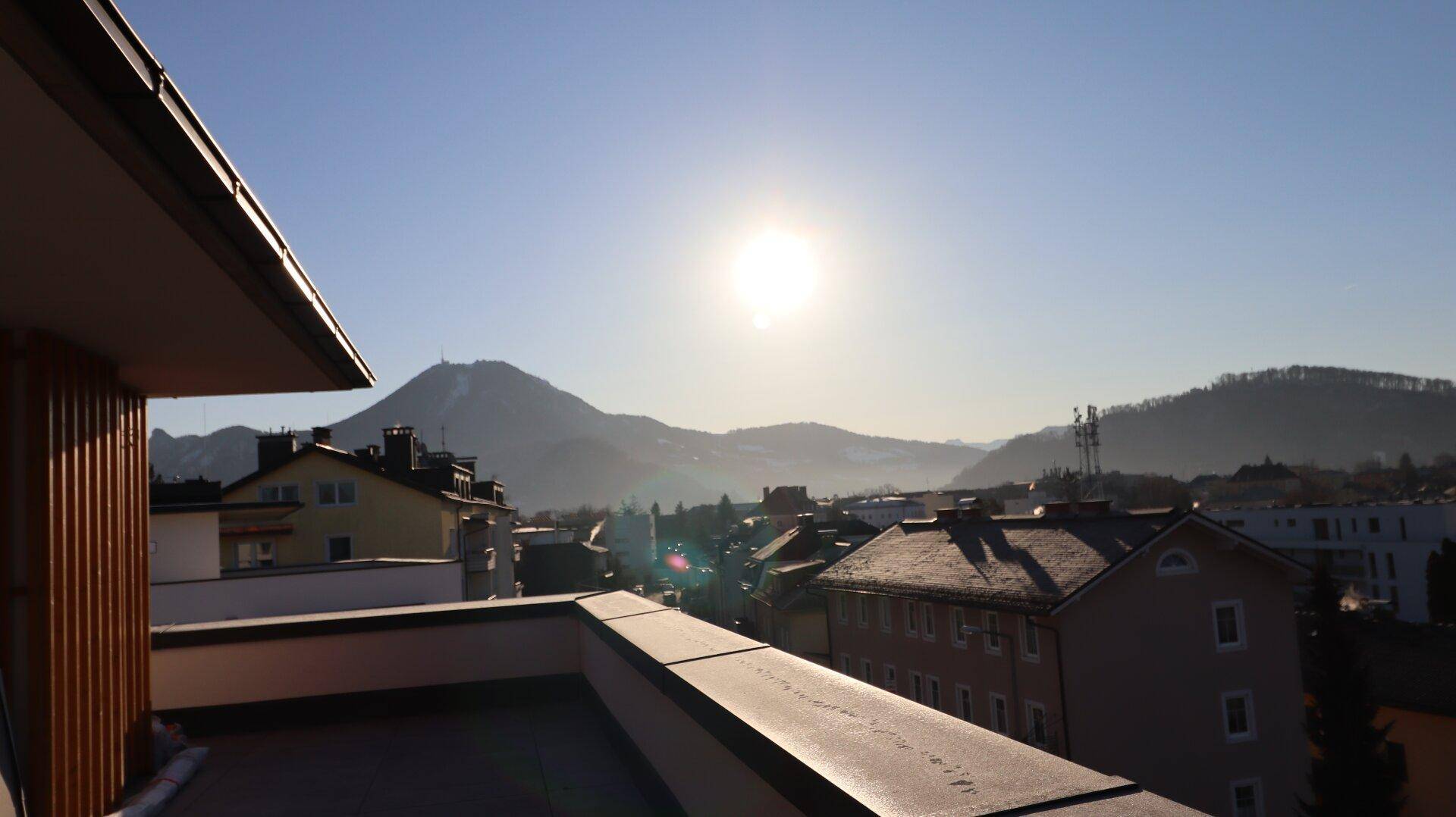 Sonnige Terrasse mit Panoramablick auf die umliegende Berglandschaft und Dächer.